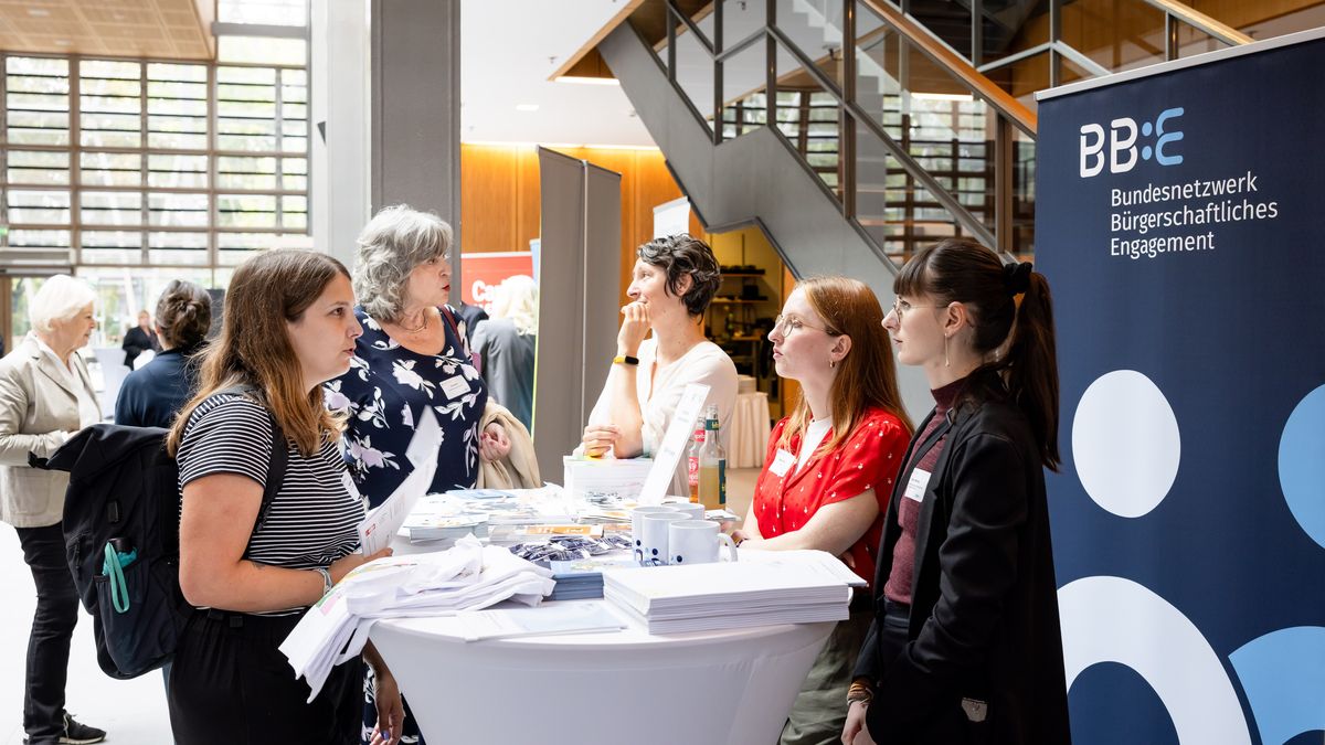 BBE-Stand © Jörg Farys / BBE Menschen unterhalten sich an einem Infostand des Bundesnetzwerks Bürgerschaftliches Engagement.