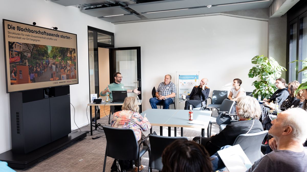 Workshop Nachbarschaftswende © Jörg Farys In einem Workshopraum sitzen Menschen und schauen auf einen Bildschirm mit einer Präsentation.