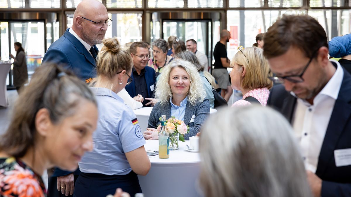 Empfang beim Auftakt © Jörg Farys / BBE Menschen stehen in einem Foyer an Stehtischen und unterhalten sich.