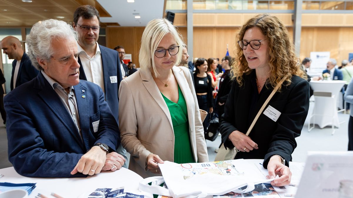 Staatsministerin Dr. Schenderlein am BBE-Stand © Jörg Farys / BBE Staatsministerin Dr. Schenderlein unterhält sich an einem Infostand mit einer Frau und einem Mann.