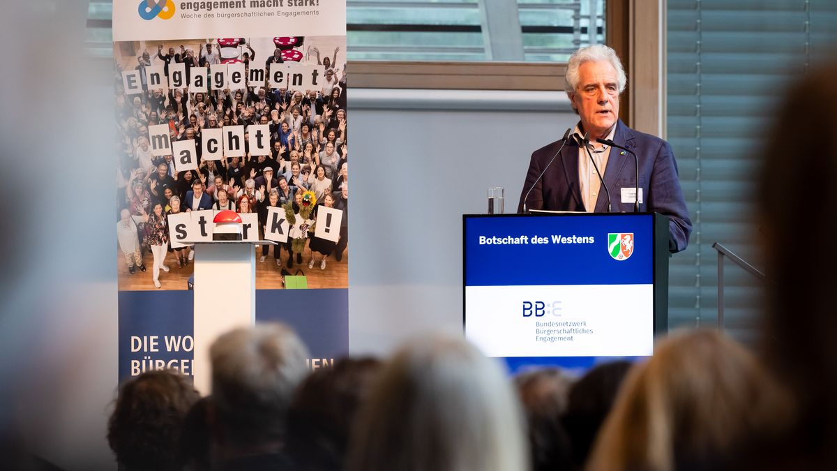Eröffnungsrede des BBE © Jörg Farys / BBE Ein älterer Mann steht hinter einem Rednerpult. Neben ihm ein Rollup von der Woche des bürgerschaftlichen Engagements.